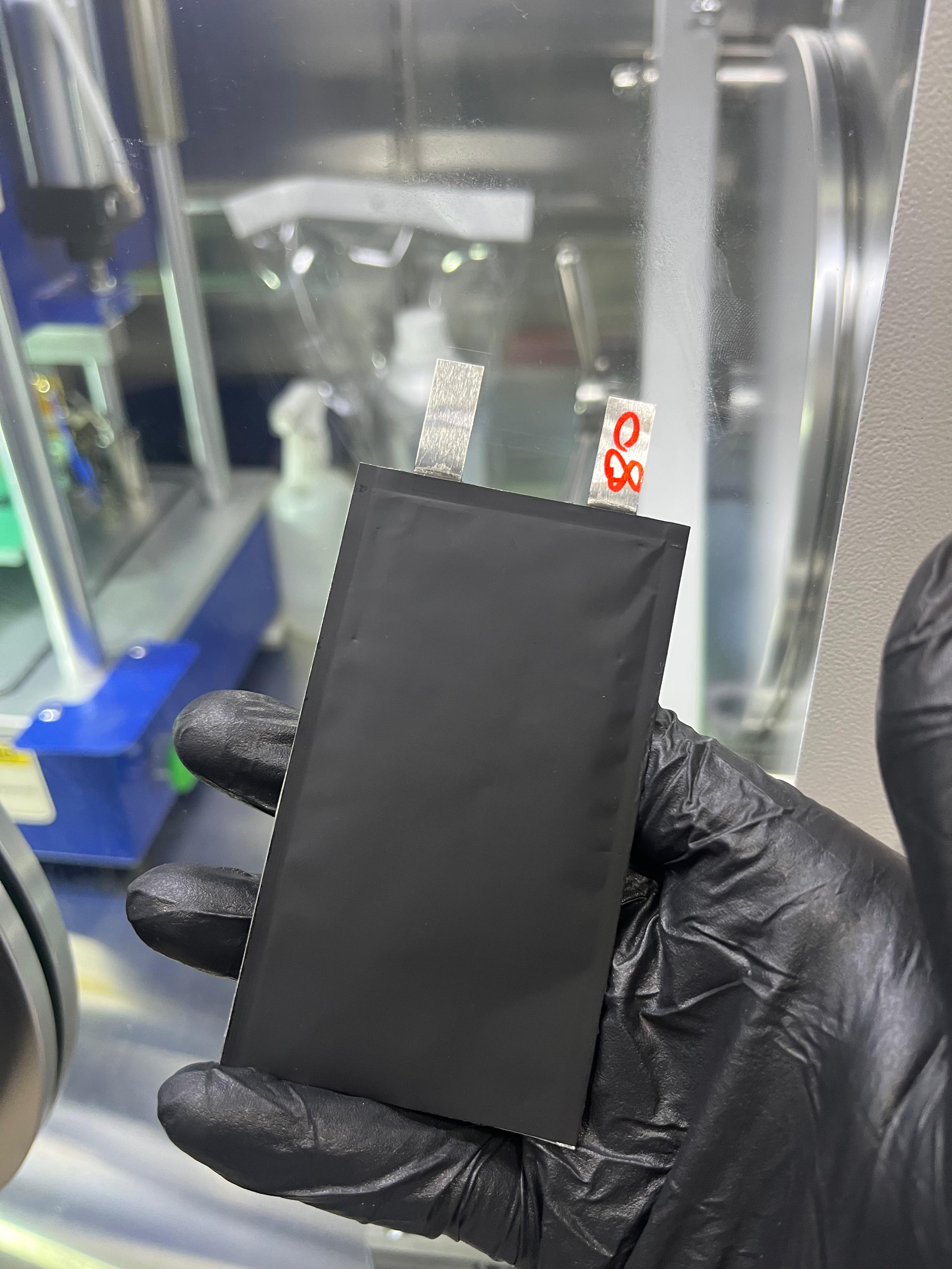 A gloved hand holding a Volfpack pouch-cell prototype